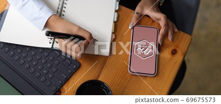 Female hands working with mock up smartphone and stationery on worktable Female hands working with mock up smartphone and stationery on worktable 69675573