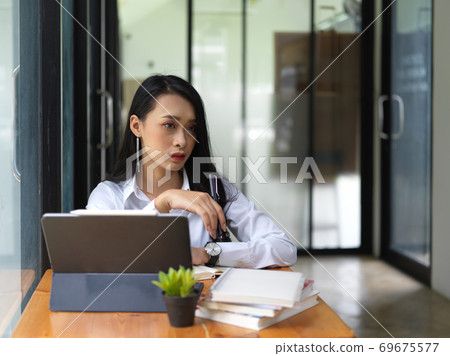Attractive female worker thinking about her project in office room Attractive female worker thinking about her project in office room 69675577