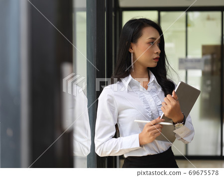 Female worker holding digital tablet while standing in front of the door Female worker holding digital tablet while standing in front of the door 69675578