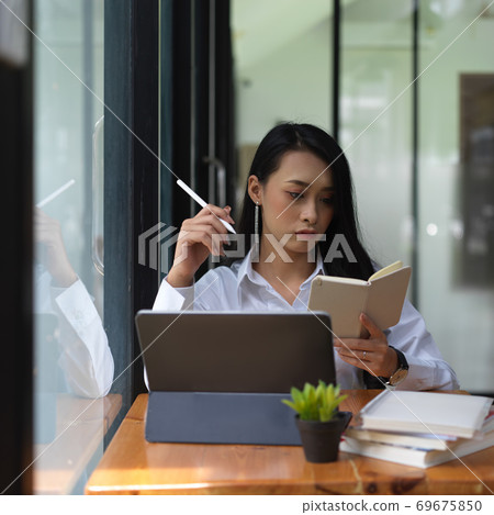 Female office worker working with schedule book and digital tablet 69675850