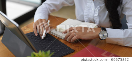 Female office worker working with digital tablet and stationery on wooden table 69675852