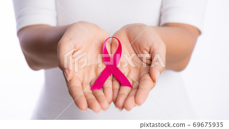 womans hands holding pink breast cancer awareness ribbon on white background. healthcare and medicine concept. 69675935