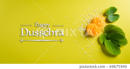 Happy Dussehra background concept. Green leaf and rice on yellow pastel background. Dussehra Indian Festival concept. Happy Dussehra background concept. Green leaf and rice on yellow pastel background. Dussehra Indian Festival concept. 69675940
