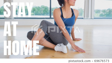 Caucasian woman practising yoga with words Stay Home during coronavirus covid19 pandemic 69676573
