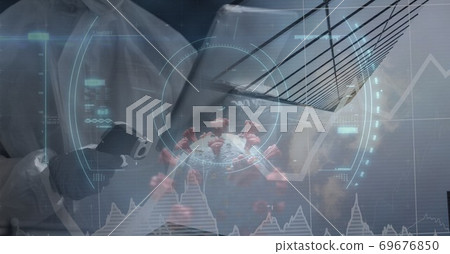 Healthcare worker using thermometer gun and digital tabler over graphs and coronavirus covid19 cell 69676850