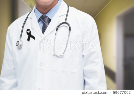 Mid section of male doctor with black ribbon on robe standing in the hospital 69677002