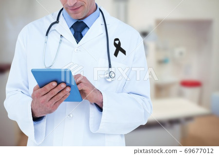 Mid section of male doctor with black ribbon on robe using digital tablet in the hospital Mid section of male doctor with black ribbon on robe using digital tablet in the hospital 69677012