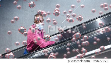 Covid-19 cells against man wearing a face mask using escalator Covid-19 cells against man wearing a face mask using escalator 69677070