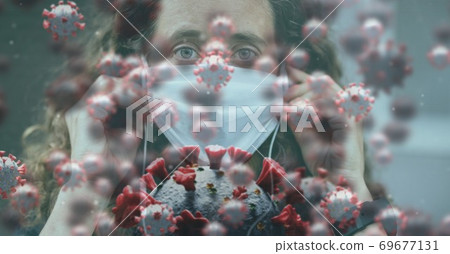 Covid-19 cells against woman in face mask wearing earphones 69677131