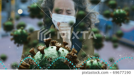 Covid-19 cells against woman wearing face mask coughing 69677190