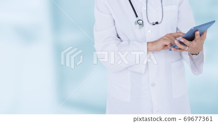 Mid section of male doctor using digital tablet in hospital during pandemic coronavirus 69677361