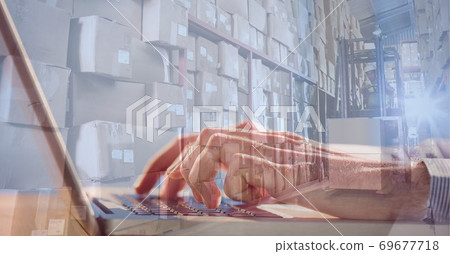 Caucasian hands using laptop shopping online over a warehouse full of boxes Caucasian hands using laptop shopping online over a warehouse full of boxes 69677718