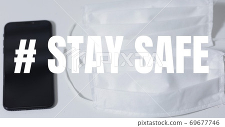 Digital illustration of multiple face masks and a smartphone on a table over a sign # stay safe Digital illustration of multiple face masks and a smartphone on a table over a sign # stay safe 69677746