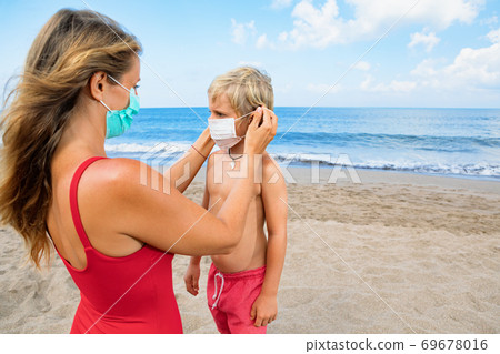 Mother put face mask on child on sea beach Mother put face mask on child on sea beach 69678016