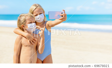 Funny kids in face masks taking selfie photo on beach 69678021