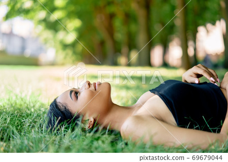 Pretty afro american woman relaxing on grass in park Pretty afro american woman relaxing on grass in park 69679044