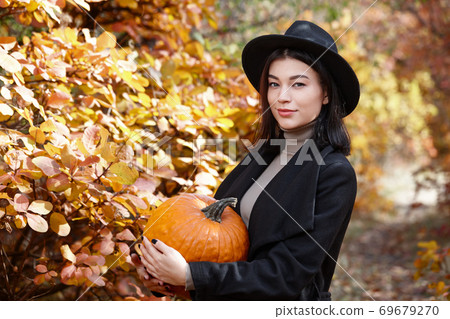 Woman in black with Halloween pumpkin 69679270