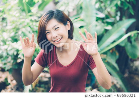 Beautiful portrait young asian woman smiling waving hand in garden at home. 69680321