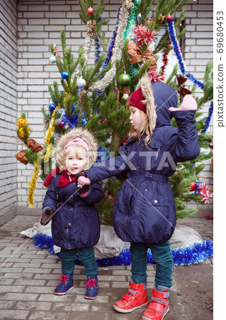 funny girls stand on street near Christmas tree. funny girls stand on street near Christmas tree. 69680453