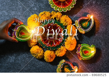 woman hand being lit clay light fire on Diya or oil lamp 69680525