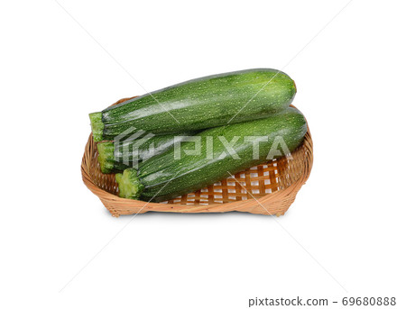 uncooked whole fresh zucchini in bamboo basket on white background 69680888