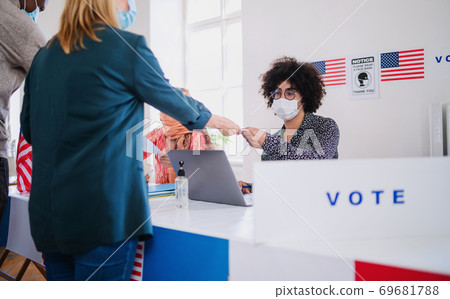 People with face mask voting in polling place, usa elections and coronavirus. People with face mask voting in polling place, usa elections and coronavirus. 69681788