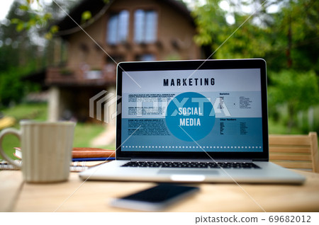 Laptop on desk outdoors in garden, home office concept. 69682012