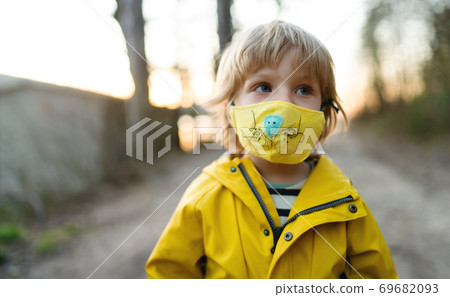 Small boy with face mask outdoors in nature, walking. 69682093