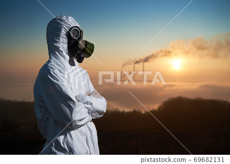 Scientist in gas mask standing on territory of thermal power plant. 69682131