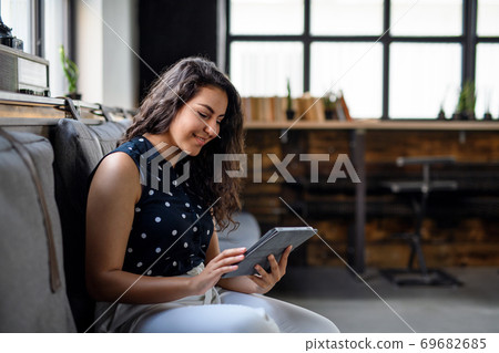Portrait of young businesswoman indoors in office, using tablet. 69682685
