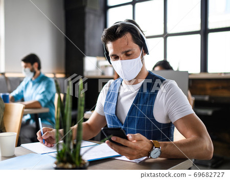 Business people with face masks indoors in office, back to work after coronavirus lockdown. 69682727