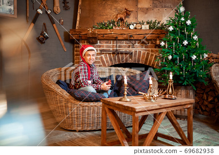 man in Santa Claus hat in new year decor of house. man in Santa Claus hat in new year decor of house. 69682938