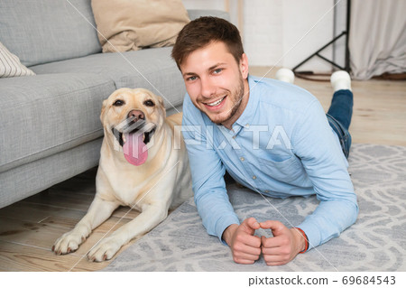 Young happy guy lying on floor with his dog 69684543