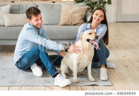 Young happy family of two sitting on floor with dog 69684649