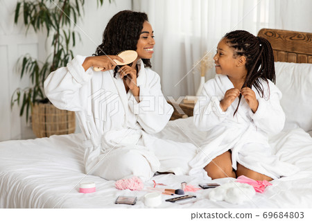 Beauty Day At Home. Black Mother And Daughter In Bathrobes Doing Hairstyles 69684803