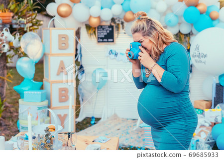 Pregnant woman taking photos of a decorated table for baby shower Pregnant woman taking photos of a decorated table for baby shower 69685933