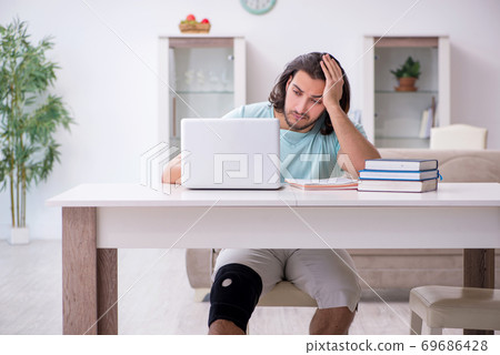 Young leg injured student studying at home Young leg injured student studying at home 69686428