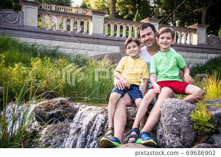 Father and two children boy little son and his brother outdoor portrait with waterfall. Father and two children boy little son and his brother outdoor portrait with waterfall. 69686902