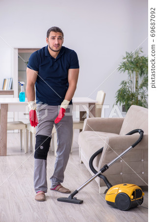 Young leg injured contractor cleaning the house Young leg injured contractor cleaning the house 69687092