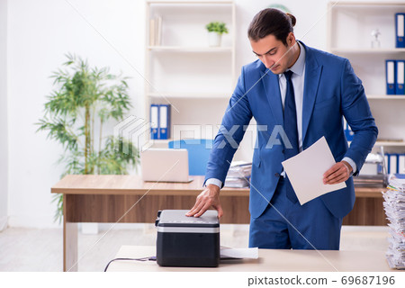 Young male employee making copies at copying machine Young male employee making copies at copying machine 69687196