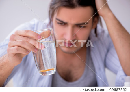 Young male alcoholic drinking whiskey at home 69687862