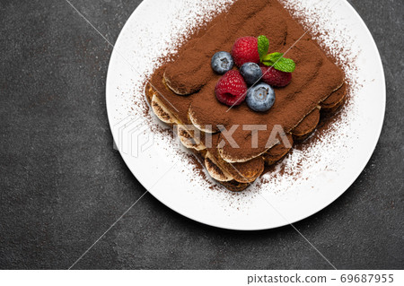 portion of Classic tiramisu dessert with raspberries and blueberries on dark concrete background portion of Classic tiramisu dessert with raspberries and blueberries on dark concrete background 69687955