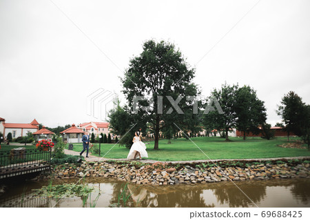 Happy wedding couple. Bride running from groom in a botanical park Happy wedding couple. Bride running from groom in a botanical park 69688425
