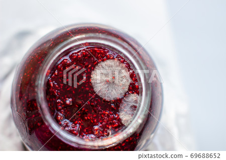 Mold in a jar of raspberry jam. Hazardous to health. Mold in a jar of raspberry jam. Hazardous to health. 69688652