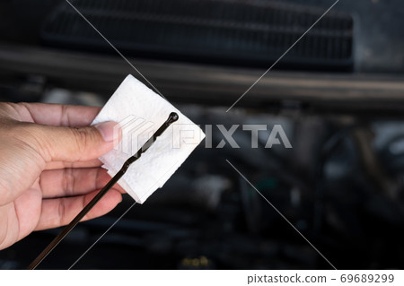 Auto mechanic checking oil level in car engine 69689299
