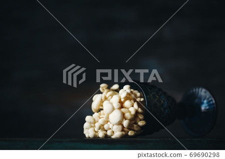 Still life with little white mushrooms putted in blue wine glass on dark 69690298