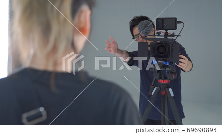 Video photographer instructing the subject to stand 69690893