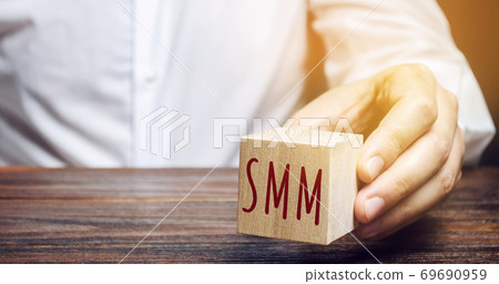 Businessman holding a wooden block with the word SMM. Social Media Marketing concept. Promote a product and service. E-marketing, digital marketing. Internet, social networks, forums, blogs Businessman holding a wooden block with the word SMM. Social Media Marketing concept. Promote a product and service. E-marketing, digital marketing. Internet, social networks, forums, blogs 69690959