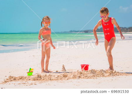 Adorable little girl playing with beach toys on white tropial beach Adorable little girl playing with beach toys on white tropial beach 69691530