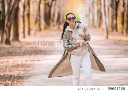 Young stylish woman walking with white dog 69691566